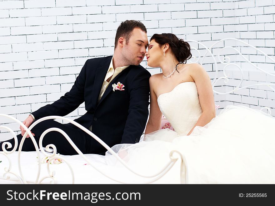 Bride and groom sitting on bed in stylish bedroom. Bride and groom sitting on bed in stylish bedroom