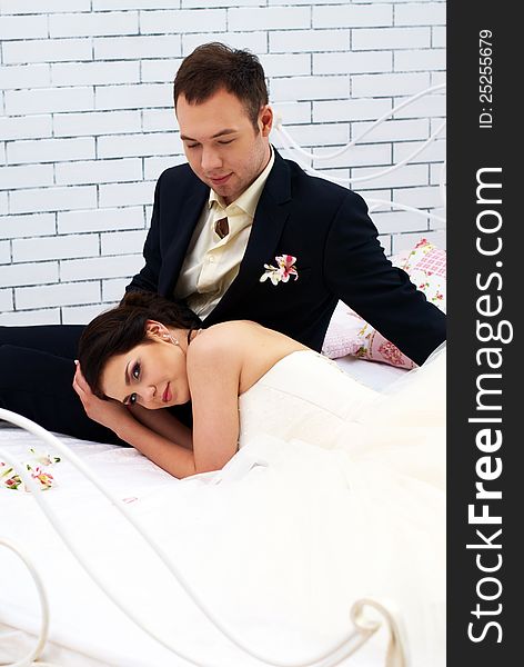 Bride and groom sitting on bed in stylish bedroom. Bride and groom sitting on bed in stylish bedroom