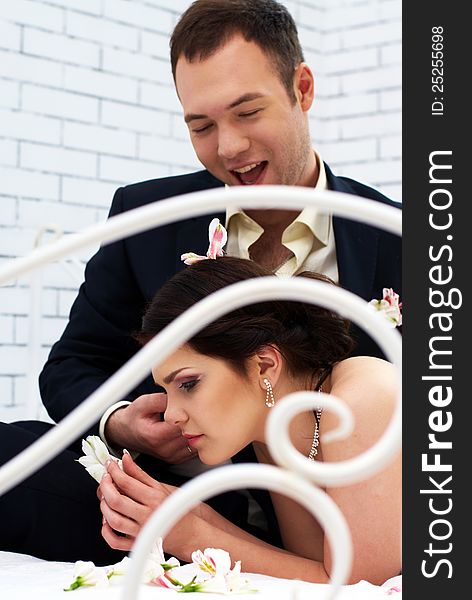 Bride And Groom Fooling In Bedroom With Orchids