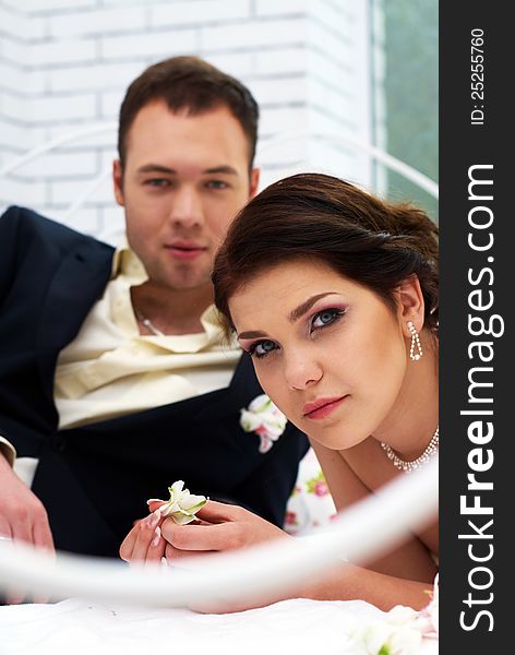 Bride and groom lying in bedroom with orchids