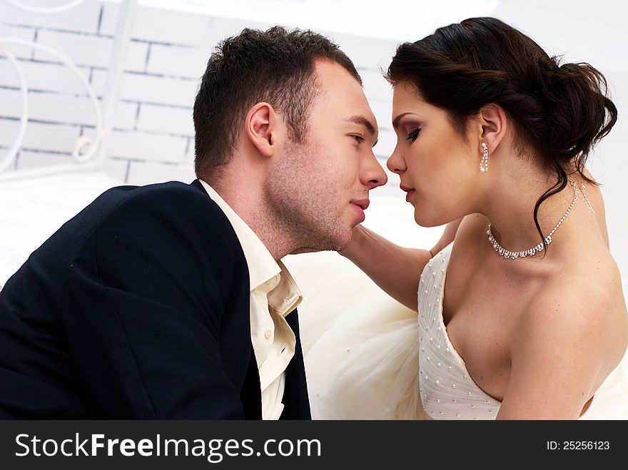 Bride And Groom Lying In Bedroom With Orchids