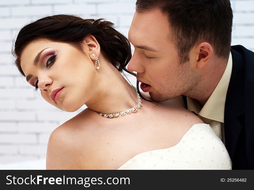 Groom Kisses Bride In White Room