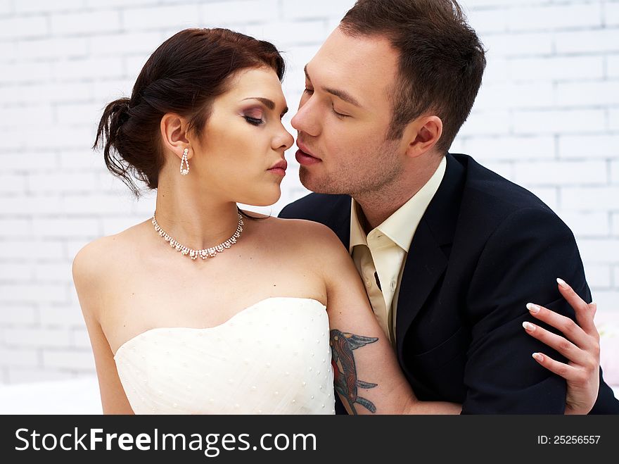 Groom kisses bride in stylish white room. Groom kisses bride in stylish white room