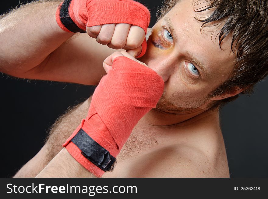 Portrait of a man with a bruise in a battle position. Clenched fists. Dark background. Portrait of a man with a bruise in a battle position. Clenched fists. Dark background.