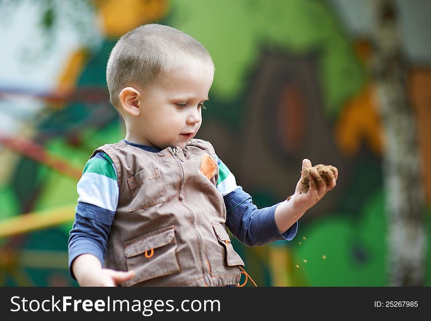 Small child plays with sand on hand