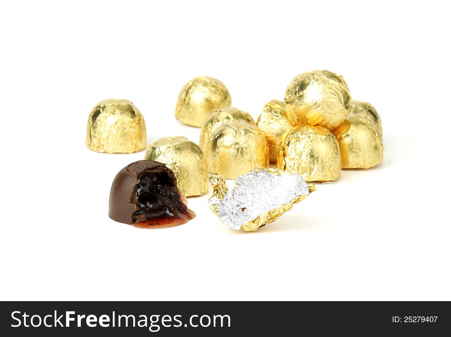 Chocolate cherry candy in golden wrappers, one half eaten