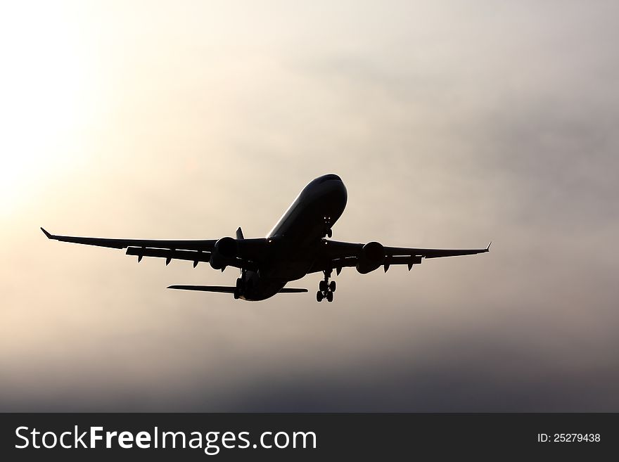 Silhouette of jet aircraft against a cloudy sky