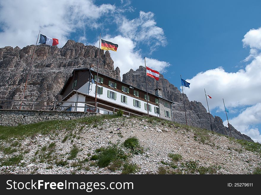 Mountain refuge with italian, french, german,austrian and UE flags, mountain and clouds in the background. Mountain refuge with italian, french, german,austrian and UE flags, mountain and clouds in the background