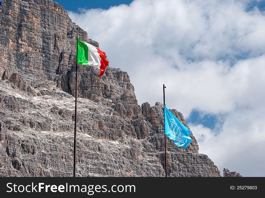 Italian and Unesco flags with mountain and clouds in the background