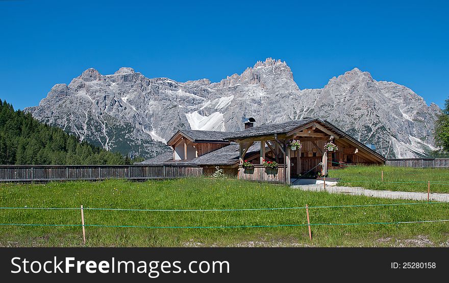Typical chalets in the Italian Alps, with flowers, wooden facade and timber and great fence and path in the front part