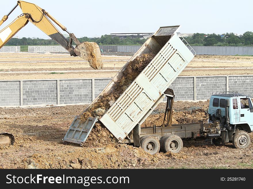 Backhoe and dump truck are working on construction site