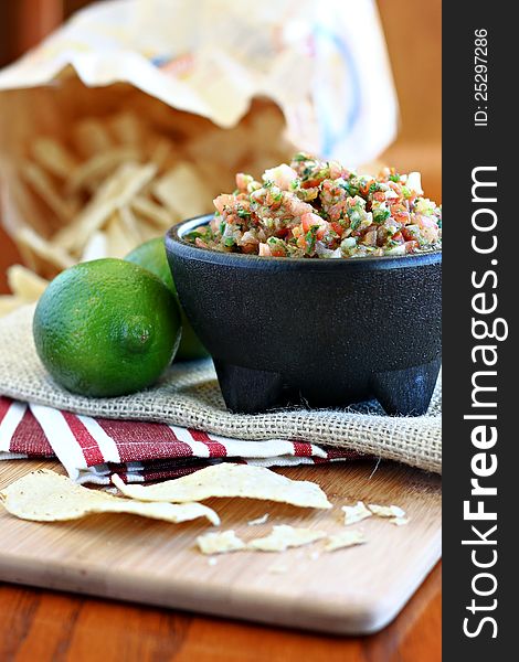 Bowl of fresh salsa with lime and tortilla chips.