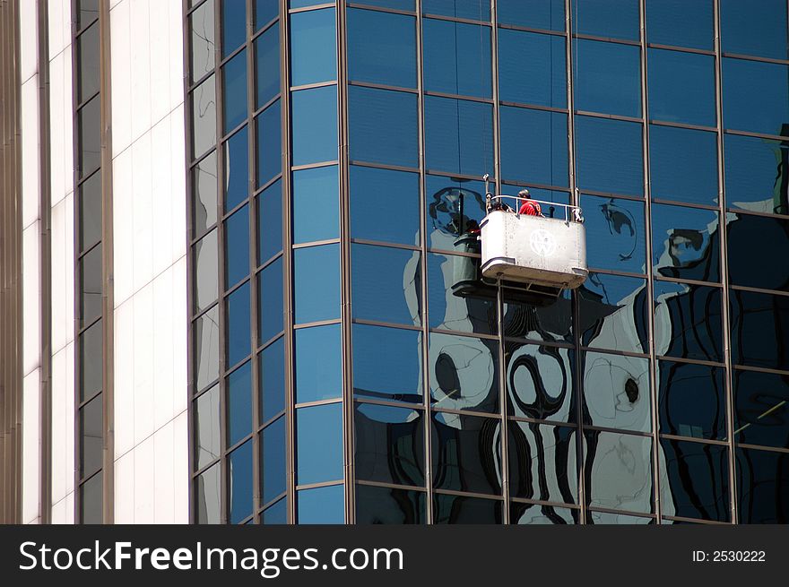 A view of window washing crew working on the side of a modern skyscraper. A view of window washing crew working on the side of a modern skyscraper.