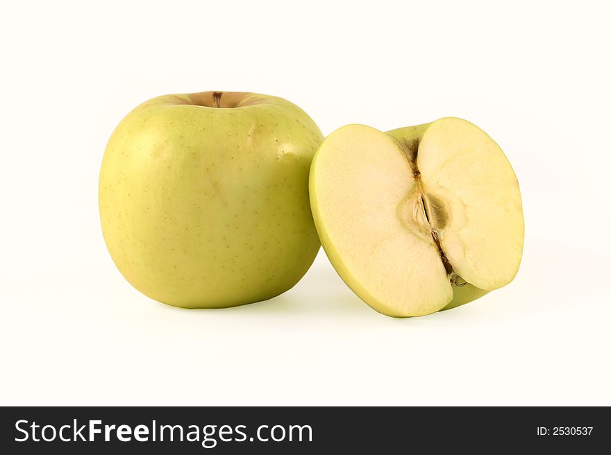 The yellow apple and half of apple are photographed on a white background. The yellow apple and half of apple are photographed on a white background