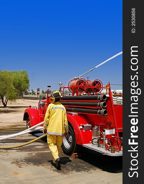 Vintage fire truck spraying water, with fireman onlooking. Vintage fire truck spraying water, with fireman onlooking.