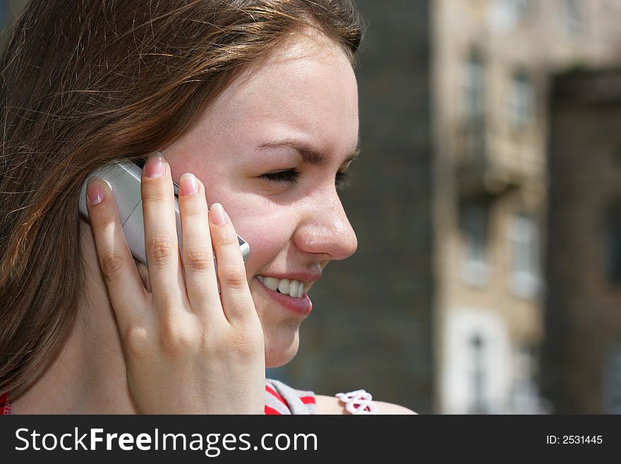 Young smiling girl with cell phone, building in the background is out of focus