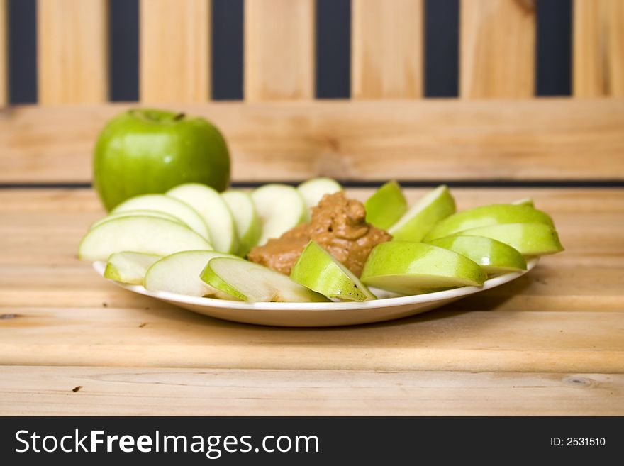 A plate of tasty granny smith apples and peanutbutter. A plate of tasty granny smith apples and peanutbutter