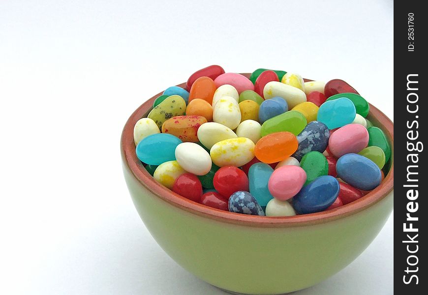 Assortment of colorful jelly beans in a mini green bowl on a white background. Assortment of colorful jelly beans in a mini green bowl on a white background.