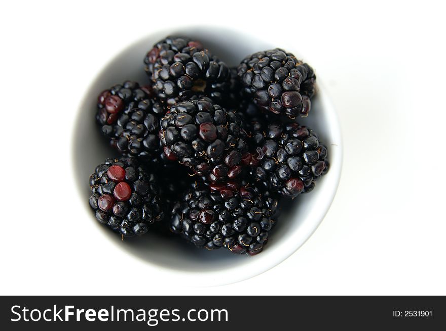 A still life of blackberries in a dish isolated on a white background