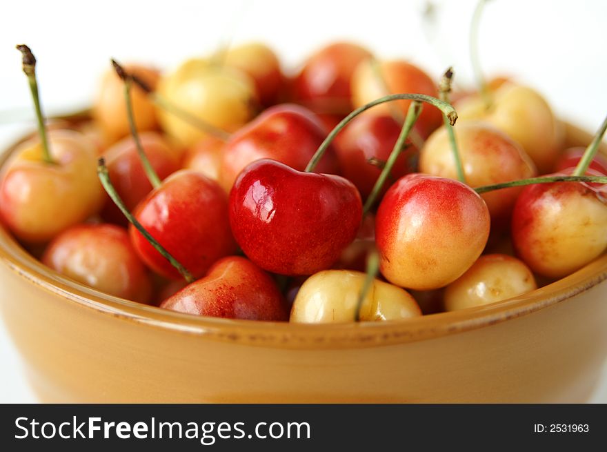 A still life of a bowl full of ripe yellow cherries. A still life of a bowl full of ripe yellow cherries