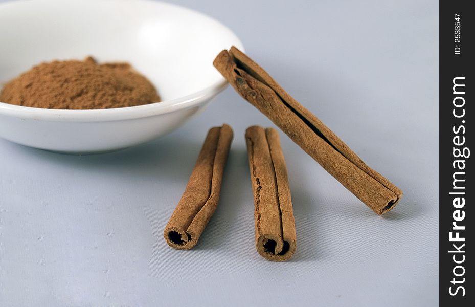 Cinnamon sticks resting next to bowl ofground cinnamon