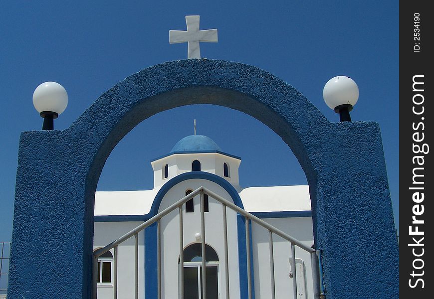 Greek church and entrance gate with clear blue sky