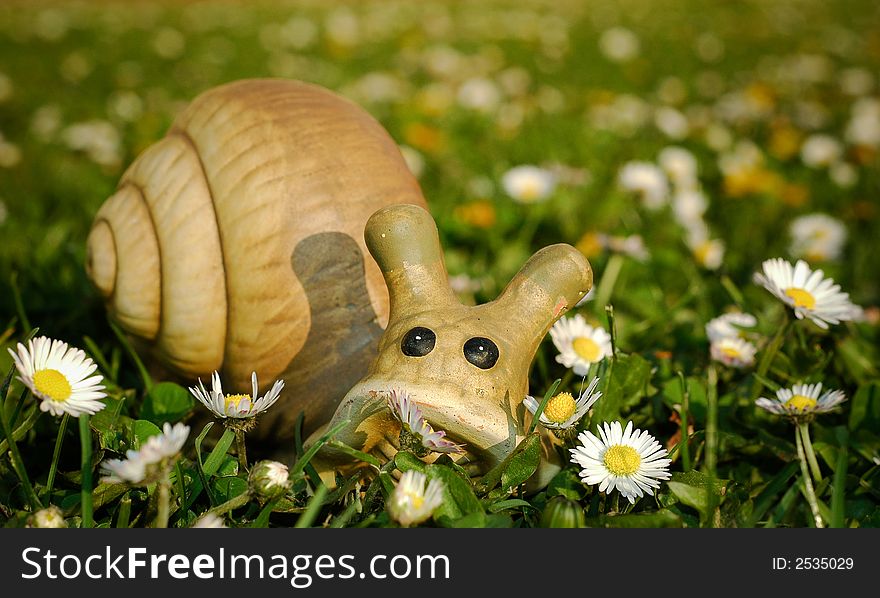 Toy snail in meadow with daisies and blurry background