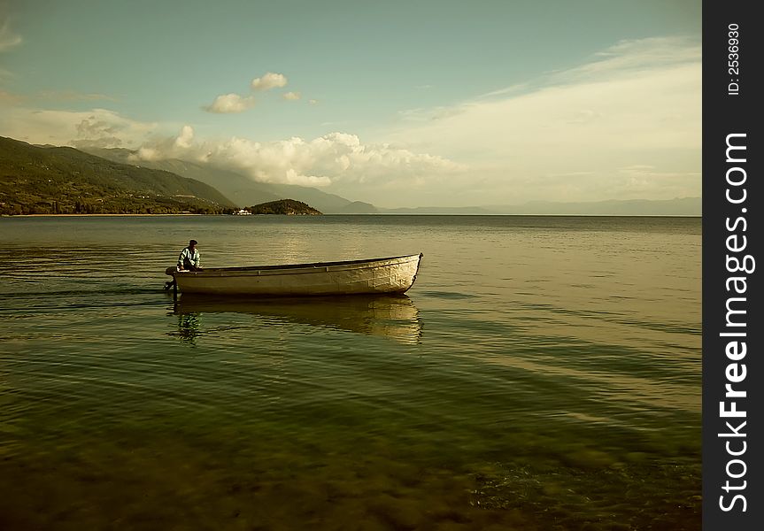 Lonely ferryman on boat in mountain lake