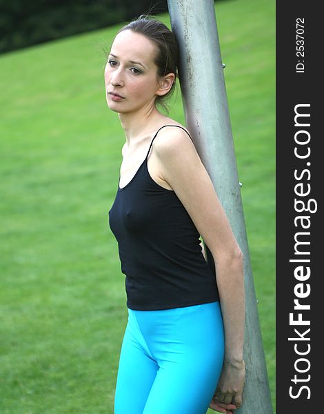 sad woman leaning against the metal pipe and having rest after workout