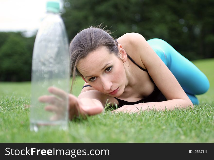 A girl reaching for a  bottle of water after aerobic. A girl reaching for a  bottle of water after aerobic