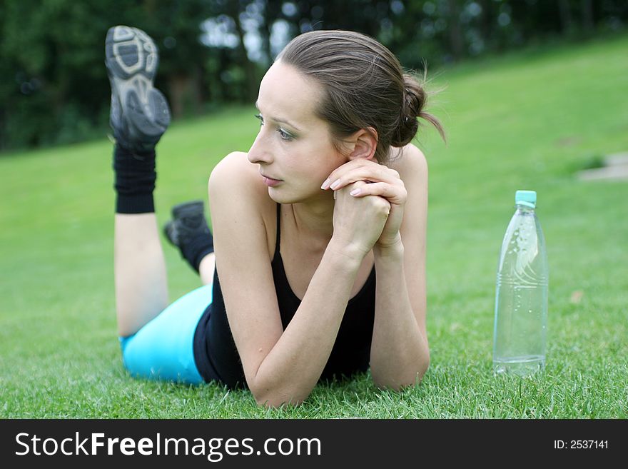 A girl lying on the grass with bottle of water  after aerobic. A girl lying on the grass with bottle of water  after aerobic