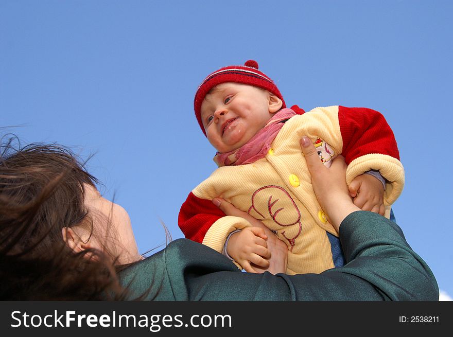 The mother lifts baby to the dark blue sky. The mother lifts baby to the dark blue sky