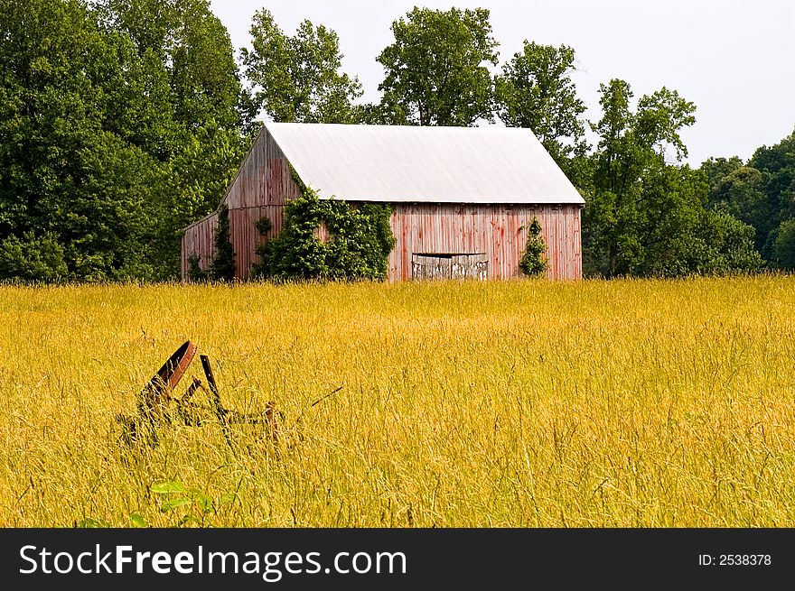 A view of an old dilapidated red barn seen across a hayfield in southern Maryland, once used to store and dry tobacco leaves. A view of an old dilapidated red barn seen across a hayfield in southern Maryland, once used to store and dry tobacco leaves.