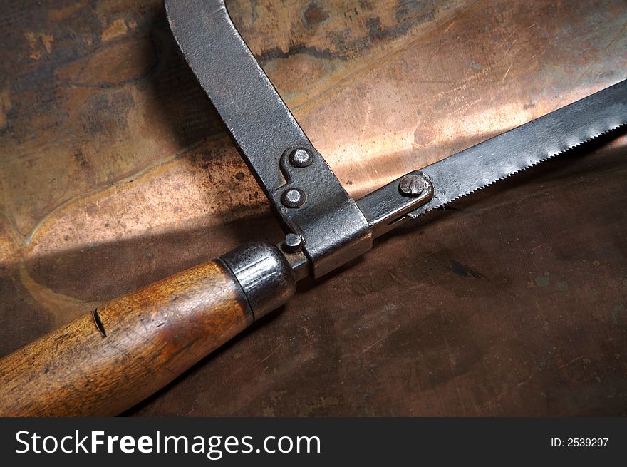 Manual saw on metal on a leaf of copper