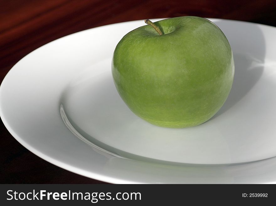 One Green Apple Standing On A White Plate