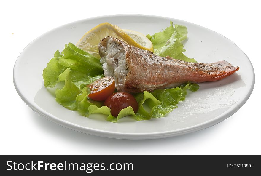 Baked rosefish with lettuce, tomato and lemon on the plate