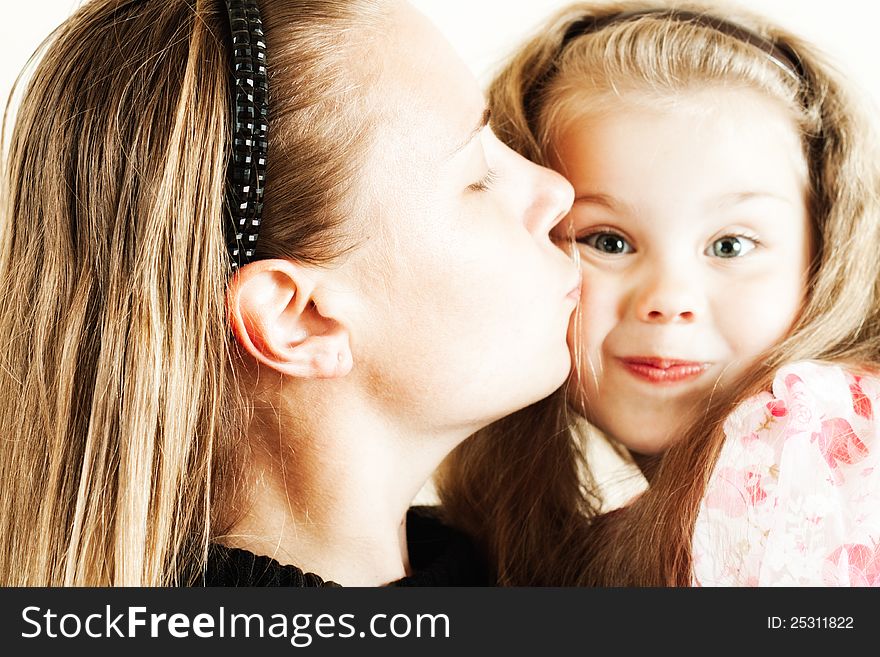 The little girl tenderly kisses his mother with his eyes closed. The little girl tenderly kisses his mother with his eyes closed