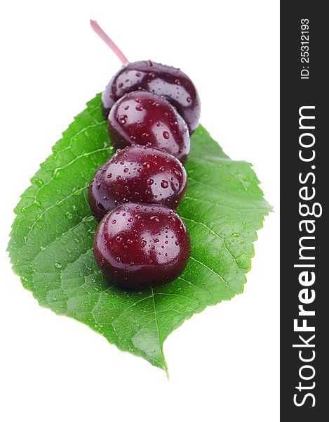 Wet cherry on a green leaf on white