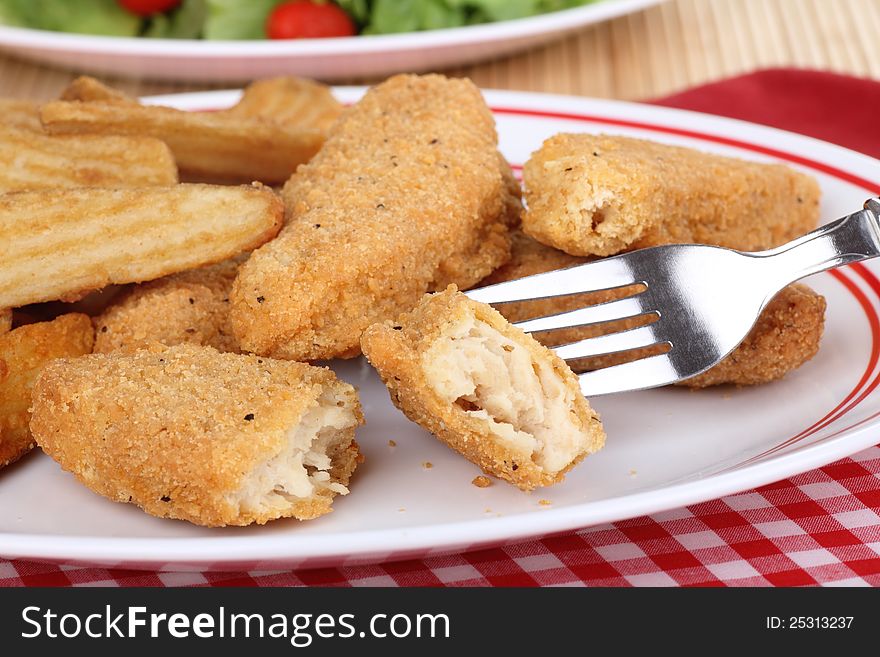 Chicken strip and fries meal with a piece on a fork. Chicken strip and fries meal with a piece on a fork