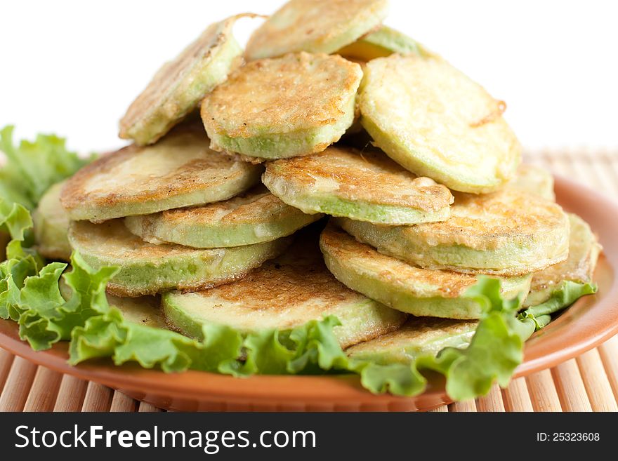 Courgettes fried in egg batter. Lot of fried zucchini on a brown dish