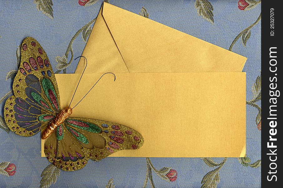 Beautiful butterfly made in fabric on texture background with golden paper sheet and envelope. Beautiful butterfly made in fabric on texture background with golden paper sheet and envelope