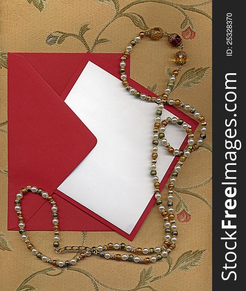 Paper sheet and red envelope on textile with necklace. Paper sheet and red envelope on textile with necklace