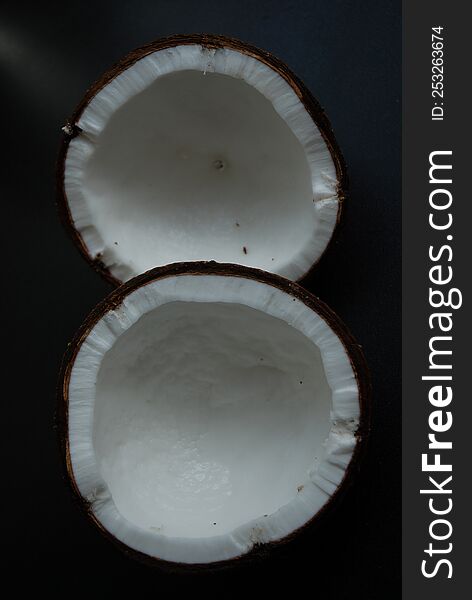 Two halves of coconut on a black background.