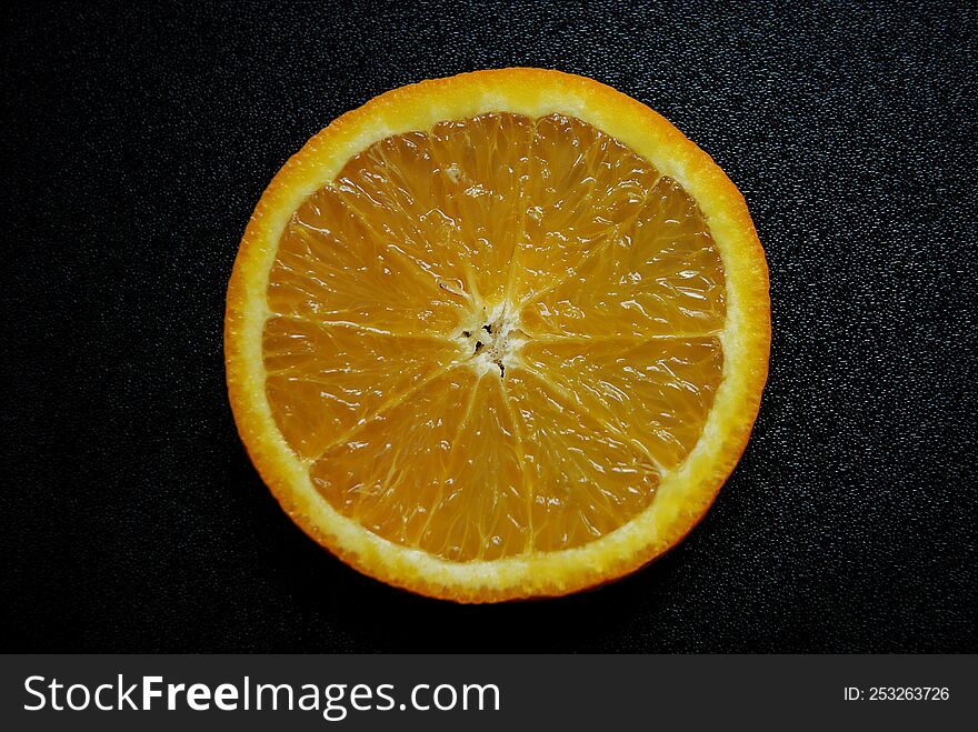 A piece of orange on a black background.