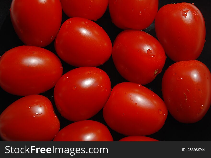 Group of red tomatoes on black background.