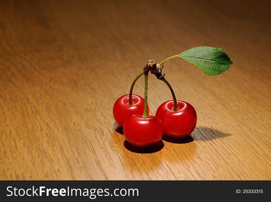 Three Cherrys with leaf on a wooden table