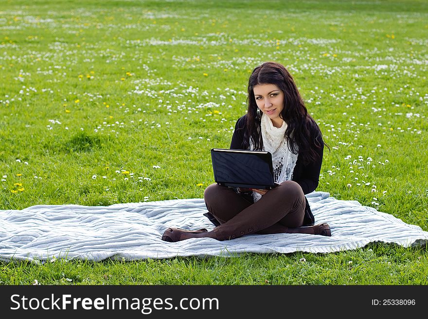 Young woman working with net-book outdoors in park on grass. Young woman working with net-book outdoors in park on grass