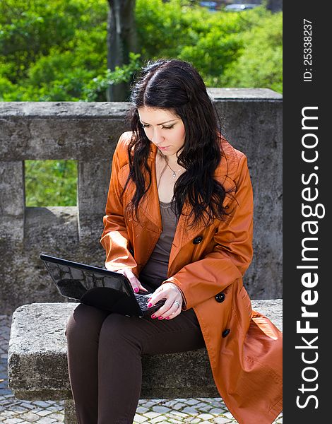 Young woman sitting on a bench and working on laptop