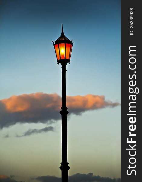 Lit old streetlamp at sunset in Argentine. Lit old streetlamp at sunset in Argentine.