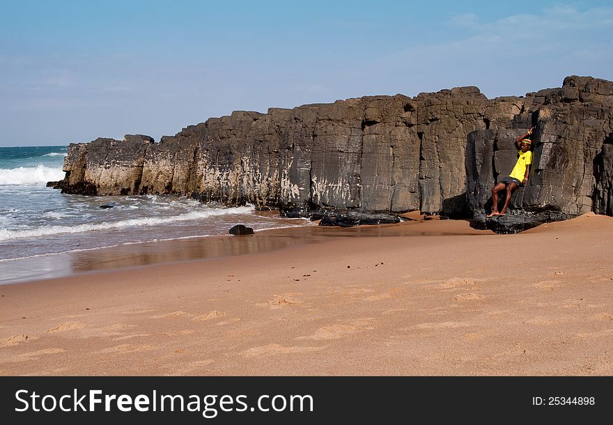 An African man leans against a rocky out crop jutting out into the sea at Ballito KwaZulu Natal North Coast, South Africa. An African man leans against a rocky out crop jutting out into the sea at Ballito KwaZulu Natal North Coast, South Africa.